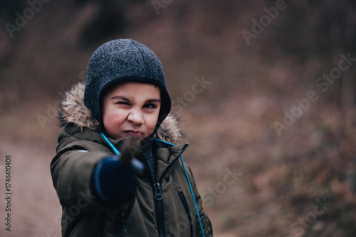 Tableau sur toile Playful boy winking and pointing finger outdoors