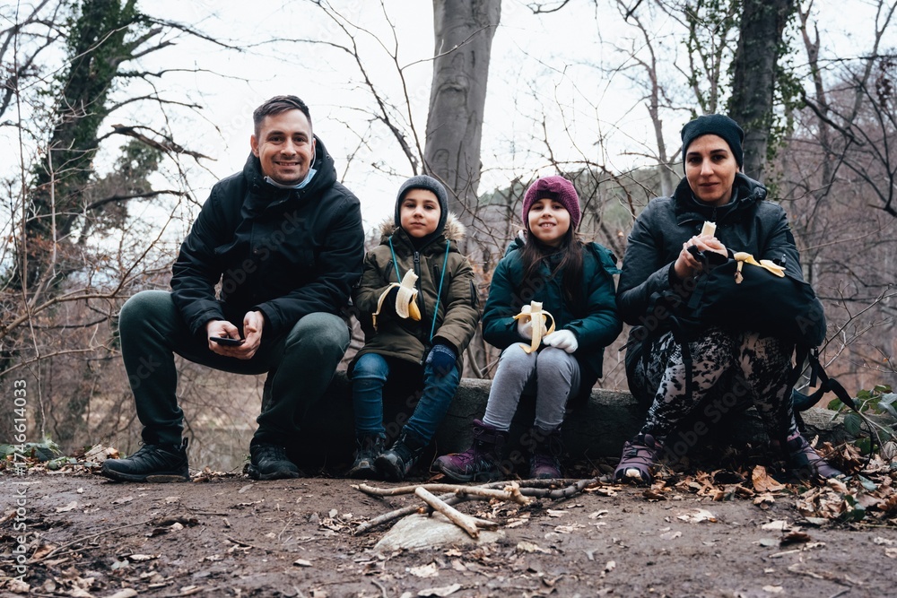 Fototapeta premium Family hiking eating bananas during winter nature break