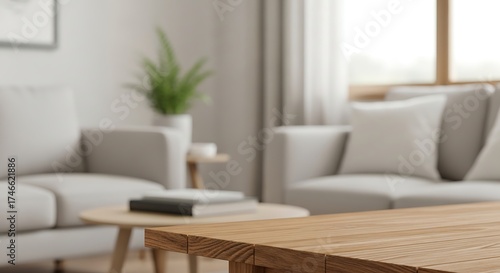 A bright living room with a wooden table in the foreground and blurred sofas, plant, and window in the background