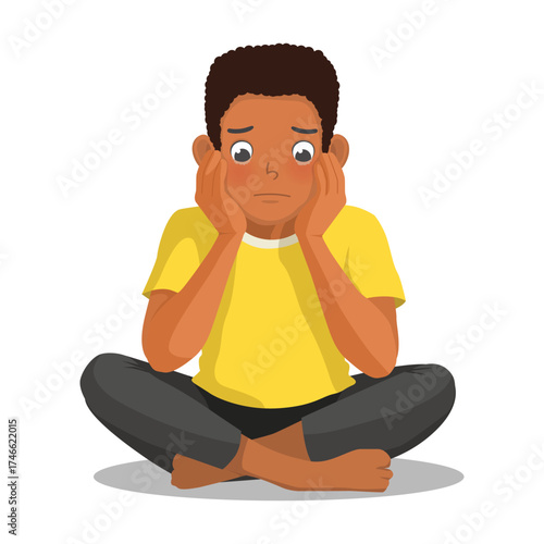 African man feeling sad, upset, and crying sitting on the floor cross legged with hands on his cheek