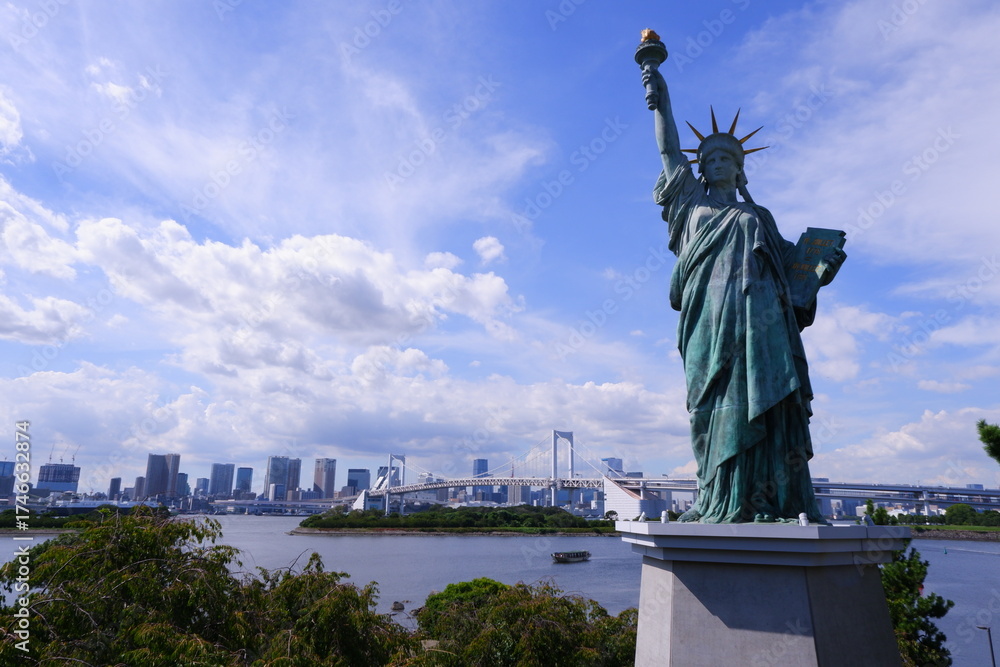 Obraz premium The Statue of Liberty replica in Odaiba, with the iconic Rainbow Bridge and Tokyo skyline across the bay, Japan.