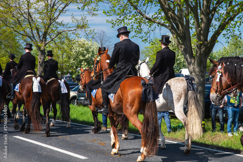 Sorbisches Osterreiten in der Lausitz. Festlich geschmückte Pferde und Reiter in schwarzer Festkleidung ziehen an einem Frühlingstag durch die Straßen.