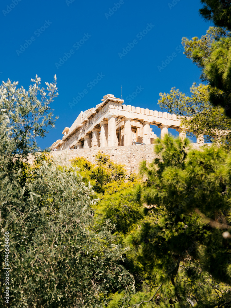 Fototapeta premium Odeon of Herodes Atticus theater on the Acropolis hill in Athens, Greece. Historic ancient amphitheater surrounded by Mediterranean trees under clear blue sky.