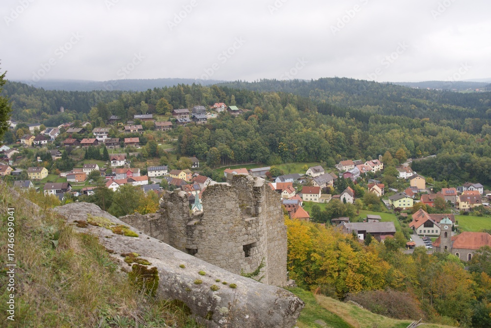 Obraz premium Ancient castle ruins overlooking picturesque village in bavarian forest
