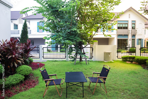 Beautiful backyard garden with outdoor furniture, green grass, and lush plants in front of a modern house. Perfect scene for real estate, home lifestyle, relaxation, outdoor living, and nature inspire