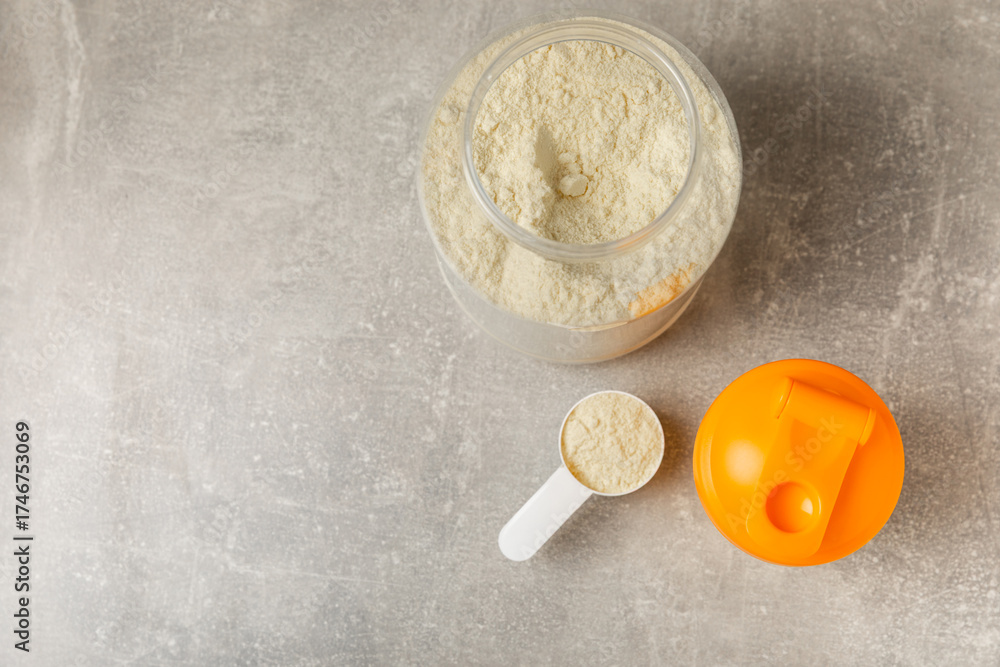 Fototapeta premium Protein shake with protein powder on a colored background. The powder is mixed with water or milk. A dietary supplement for a balanced diet. Whey protein. Fitness and gym diet nutrition.