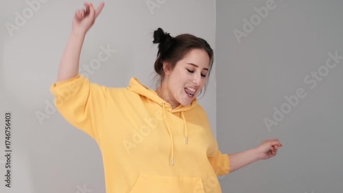 Pretty girl in a yellow sweater having fun on the bed - jumping and dancing. brunette