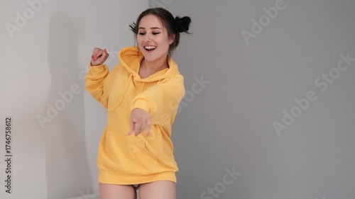 Pretty girl in a yellow sweater having fun on the bed - jumping and dancing. brunette