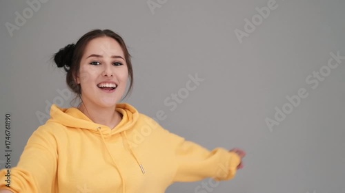 Pretty girl in a yellow sweater having fun on the bed - jumping and dancing. brunette