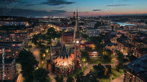 Stunning evening view of Gotheborg, Sweden showcasing city lights and historic architecture. Flying around Oscar Fredriks Church in Gotheborg with citylights and red sunset sky