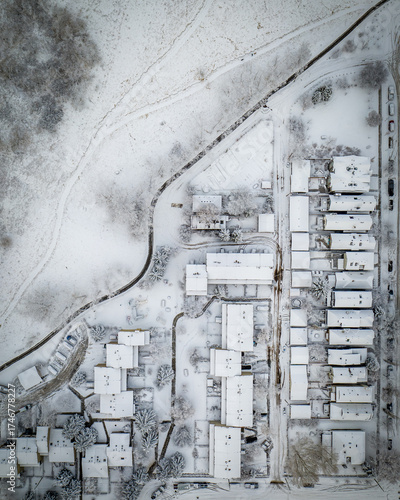 Aerial view of snow-covered rooftops and quiet streets create a serene, monochrome tableau, with the winding path adding a touch of dynamism, Calgary, Alberta, Canada.