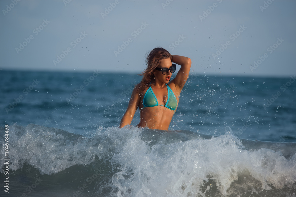 Fototapeta premium Confident Redhead in Turquoise Bikini Standing in Ocean Wave