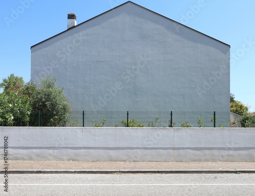Wallpaper Mural White plaster fence with wire mesh on top. Plants, single house and sky on behind. Sidewalk and street in front. Background for copy space Torontodigital.ca