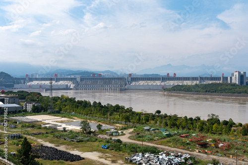 Yichang Three Gorges dam stands majestically across a wide river under a cloudy sky, with mountains in the distance.