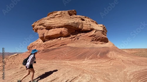 Woman hiking at Beehive and New Wave trails in Glen Canyon National Recreation Area near Page, Arizona. Sandstone outcroppings, windswept rock formations, desert landscape.