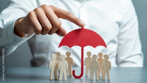 Insurance Coverage & Protection: The hand of a professional holds a red umbrella over a group of miniature figures, representing insurance coverage and protection, a shield against uncertainty. 
