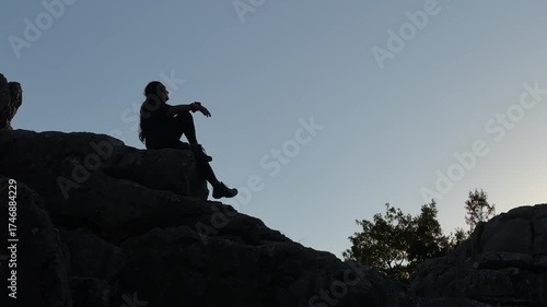 The lady on the cliff is watching the magnificent views at the top of the mountains