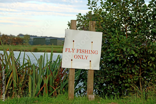 Old Fly Fishing Only Signboard at a Rural Trout Fishery in Summer