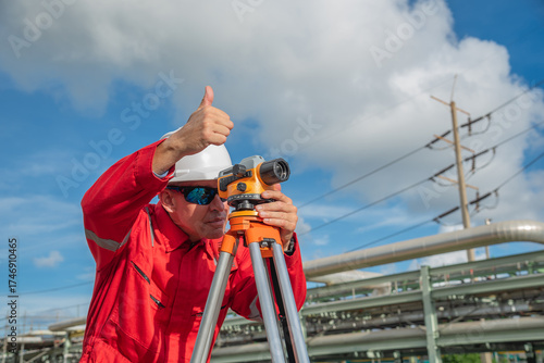 Man engineer using theodolite outdoors and thumbs up