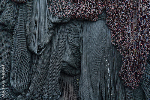 Marine scene showing black hanging fishing nets overlapped with thick red mesh, creating strong texture and contrast.
