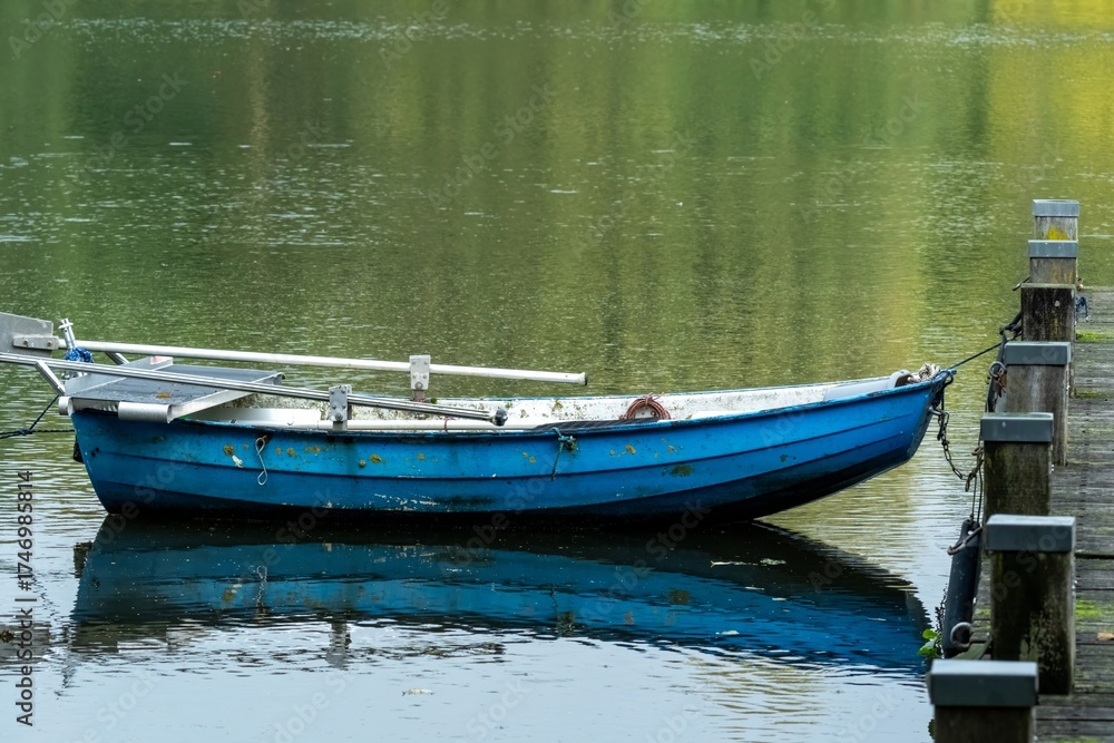 Obraz premium Blue rowing boat moored at rustic dock