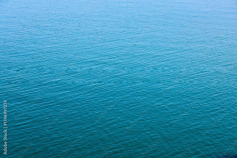 Obraz premium Water Surface Texture. Beautiful Blue Waves. Global Warming. Water texture. View of a lake surface texture. Seascape from top perspective. Close Up waves. Turquoise sea water. Sea water in low tide.
