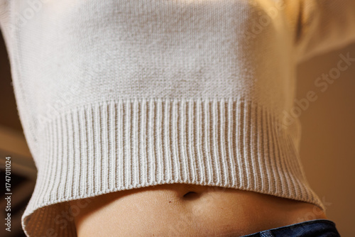 Woman wearing casual sweater showcasing midriff for fashion or wellness