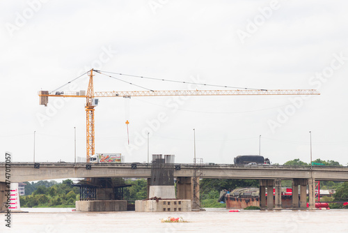 tower crane over river bridge under construction with traffic on roadway