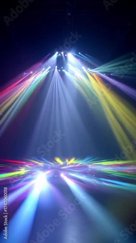 A vibrant light show bursts into action with beams of colorful light sweeping across the stage