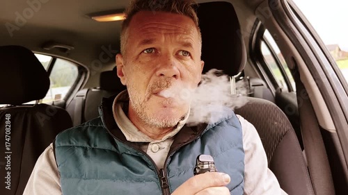 Man is vaping, using e cigarette inside of car