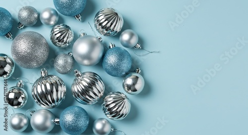 Assortment of silver and blue Christmas ornaments, including glittery and ribbed finishes, scattered on a pale blue background.