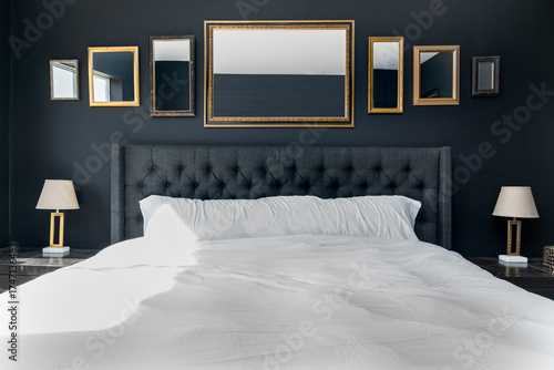 Photography Luxurious bedroom with bed tufted headboard, mirrors, and gold lamps