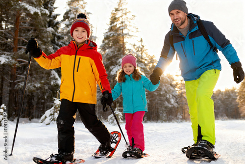 Family enjoying winter adventure in snowy forest with snowshoes and smiles