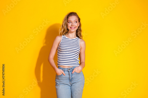 Stylish young woman in casual summer attire posing confidently against a vibrant yellow background, exuding cheerful vibes