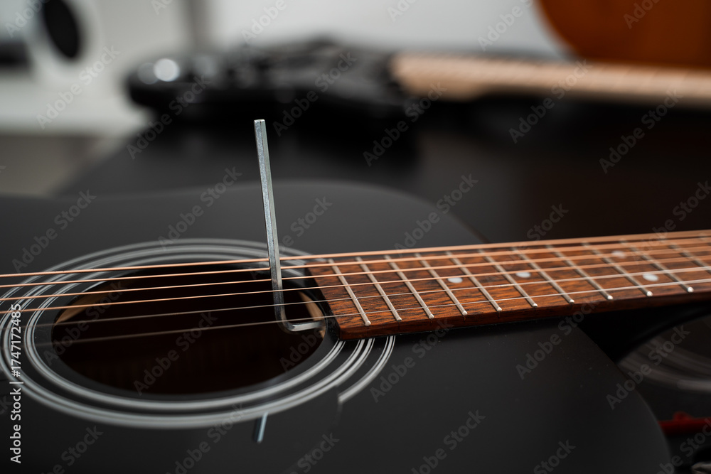 Obraz premium Adjusting a guitar truss rod. Guitarist adjusting the truss rod inside the acoustic guitar. Fine-tuning an acoustic guitar truss rod with precision using an Allen key.