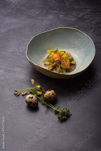 Elegant presentation of steak tartare with a quail egg, pickles