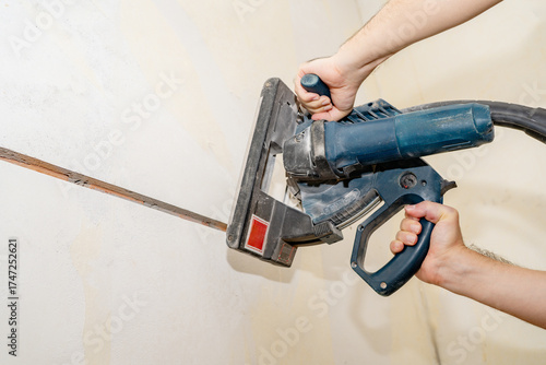 Valokuva Electrician using wall chaser to cut a groove in a concrete wall for electrical wiring installation