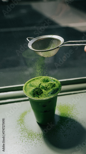 A person is pouring matcha into a cup