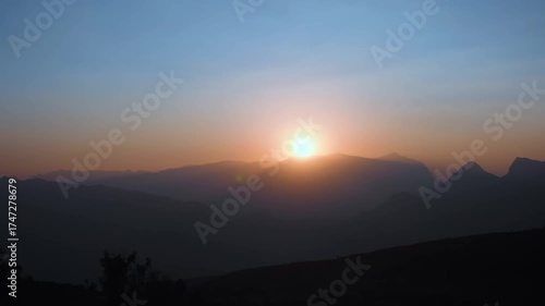 Wallpaper Mural A stunning time lapse or slow motion video of the sun rising over the rugged, silhouetted peaks of the Hajar Mountains in Jebel shams Oman. The sky transitions from deep blue to vibrant orange and yel Torontodigital.ca