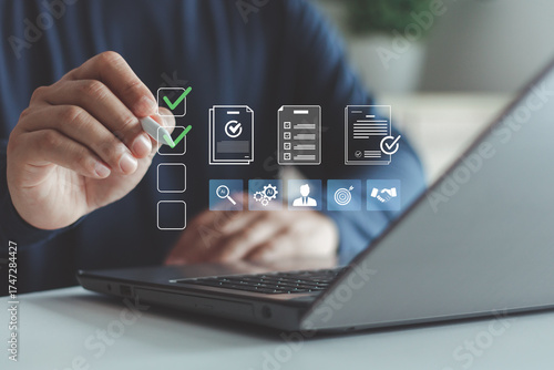 Businessman using laptop with virtual checklist and document icons, task management, digital workflow, productivity optimization in modern business operations. Human resources management concept.