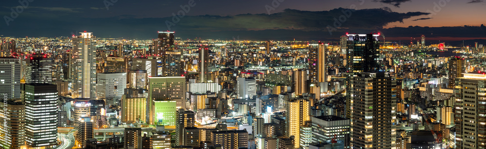 Naklejka premium Osaka panorama. Metropolis in Japan. Osaka in evening. High-rise buildings under night sky. Bird -eye view of Osaka. Downtown in Japanese province. Cityscape of Japan. Skyscrapers on Honshu island.