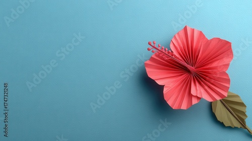 A single red origami hibiscus flower on a blue backdrop