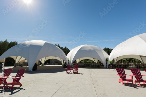  nice view of pavilion garden with white tents, red chairs,recreational ground on sunny day and blue sky background