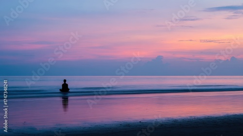 Person in meditation pose on beach during sunset