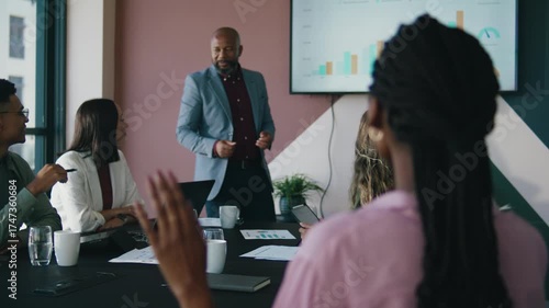 Black businesswoman with hand raised during presentation in meeting room at office