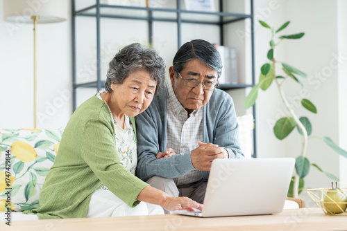 リビングでパソコンに悩むシニアの夫婦