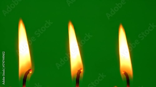 Three Bright Candle Flames Ignited Against a Vibrant Green Background Symbolism of Hope Celebration and Light