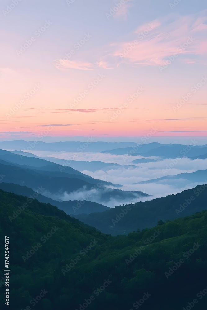 Obraz premium Majestic sunrise over rolling green hills covered in mist and fog, with layered mountain ranges fading into the horizon under a soft pastel sky, creating a peaceful natural landscape background for de