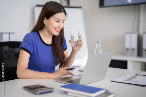 Asian adult woman working laptop computer office remote business tasks online productivity relaxed casual setting efficient creative problem solving modern workspace daily routine