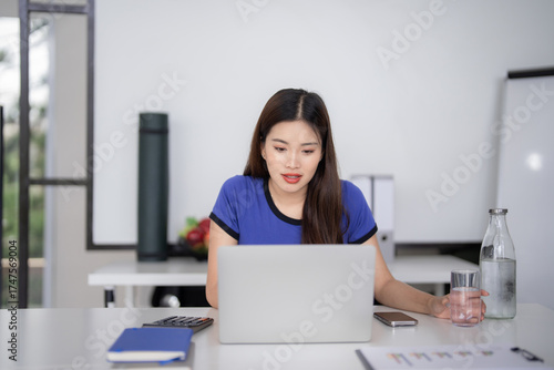 Free Download Asian businesswoman working laptop computer home office professional tasks productivity modern workspace freelancer focused entrepreneur casual work setup remote employment - GFXLoad